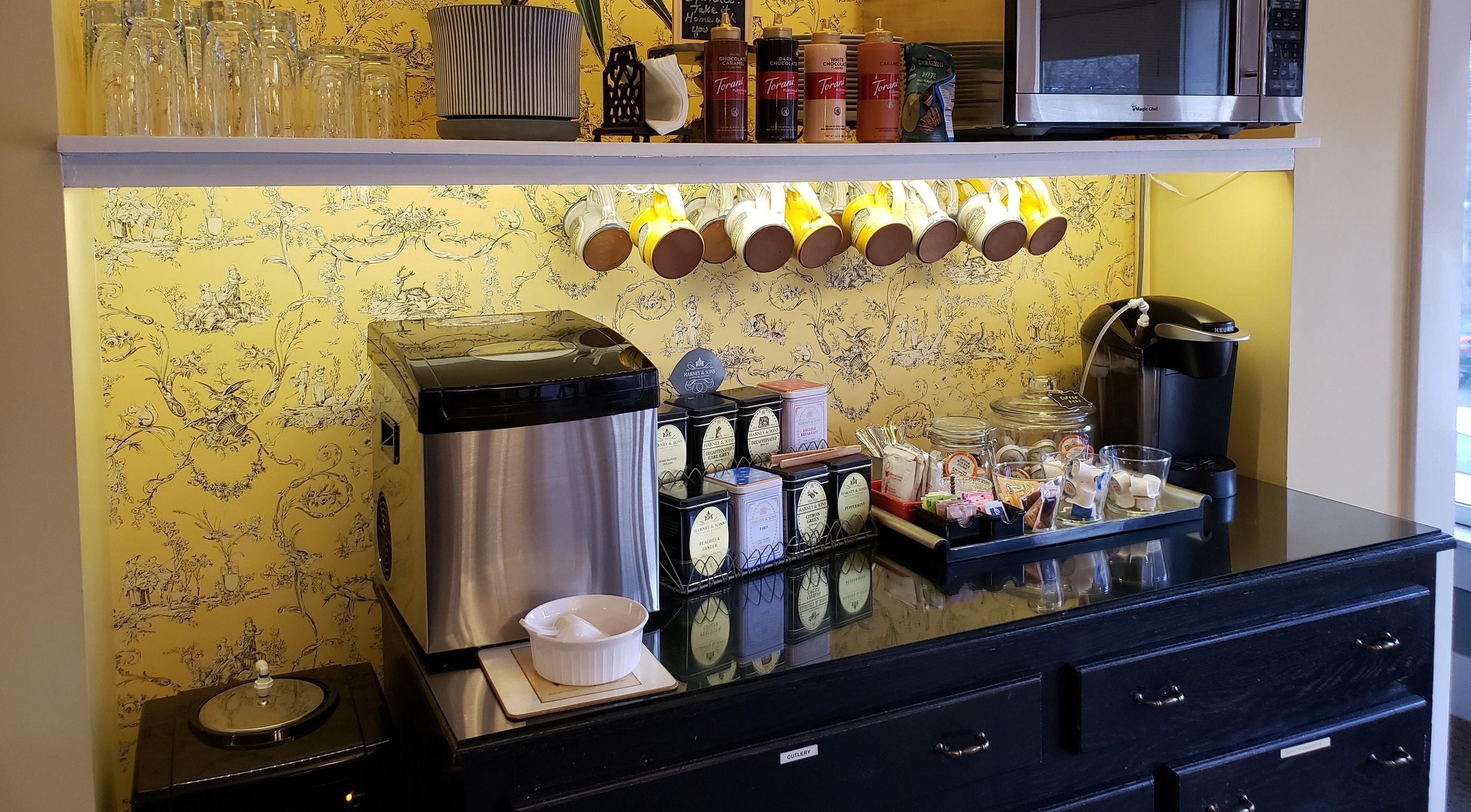 a breakfast bar with a coffee maker, tea, and microwave