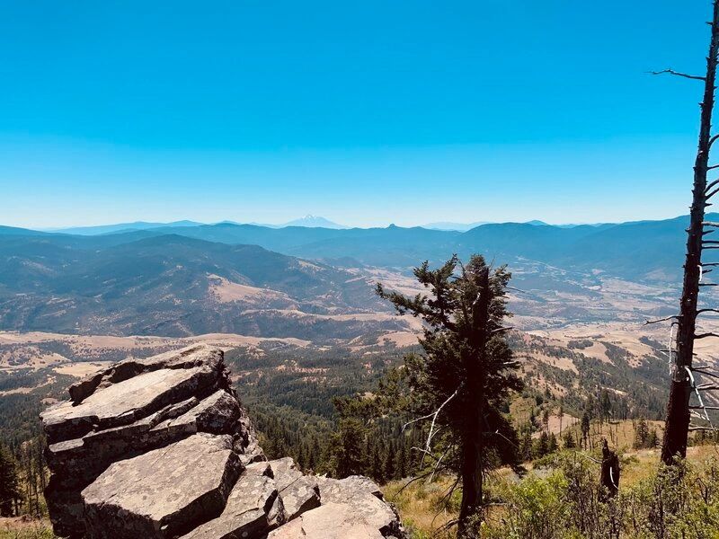 a view of mountains and trees under a blue sky
