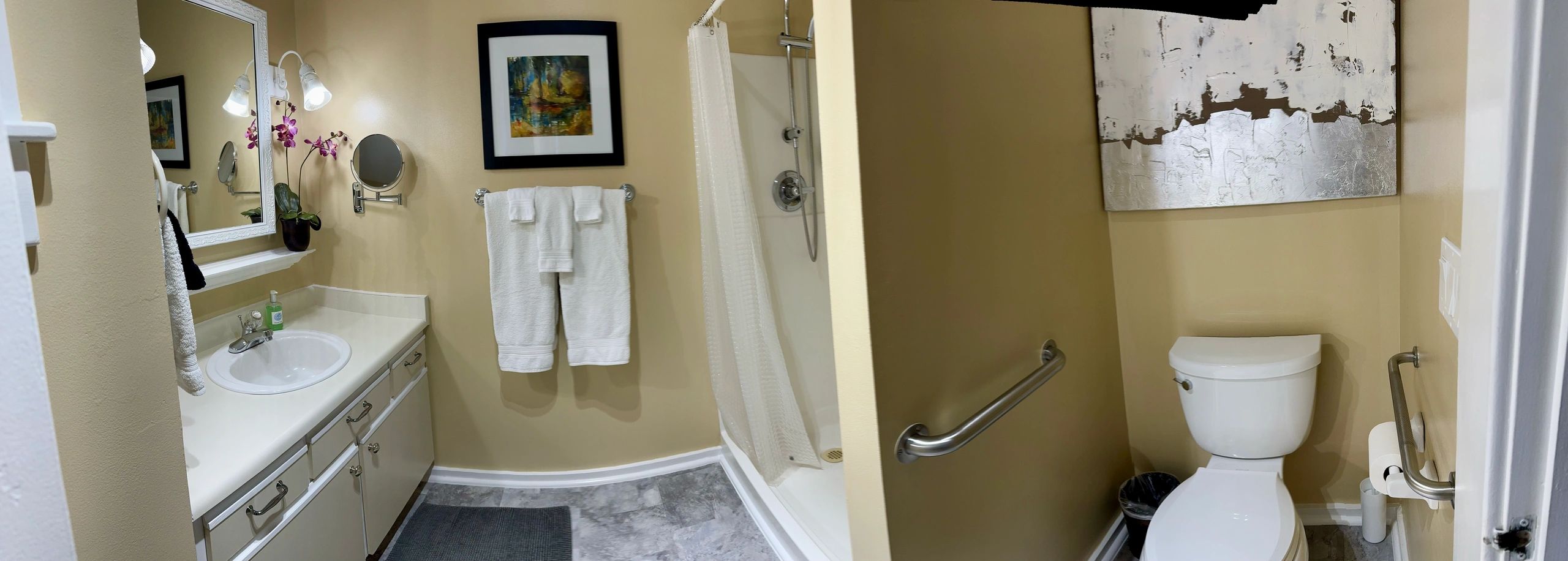 A clean bathroom with a sink, toilet, shower, and towels.