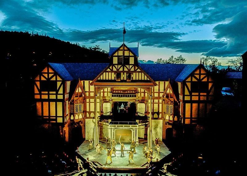 A half-timbered building with a lit-up theater performance at night