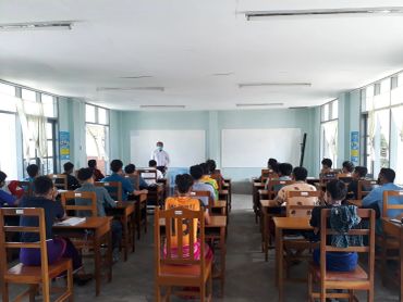 Classroom with students and a teacher wearing masks.