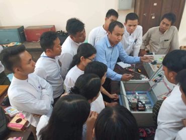 A man teaching a group of students about electronics.