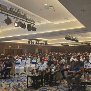 Large conference with attendees seated in a modern hall.