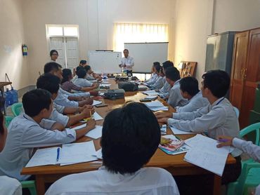 Group meeting or class in a spacious room with a presenter.