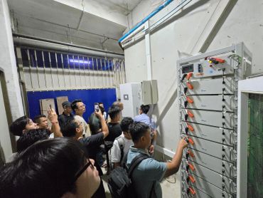 Group of people inspecting electrical equipment.