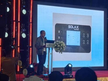 Man presenting on stage with SOLAX POWER displayed.