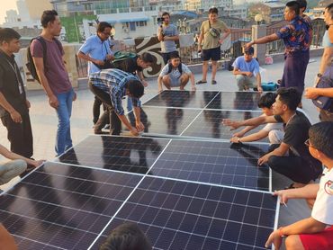 Group assembling solar panels on rooftop.