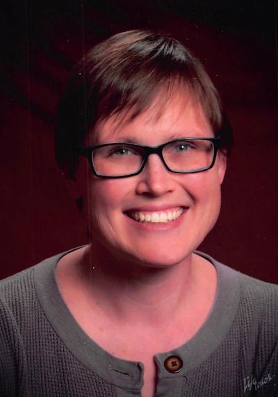 A smiling acupuncturist with short hair and glasses. 