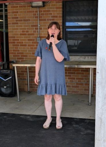 Woman in a blue dress speaking into a microphone.