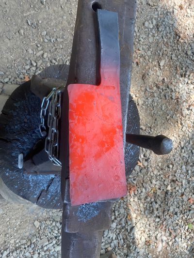 A red-hot metal piece on an anvil, glowing from intense heat.