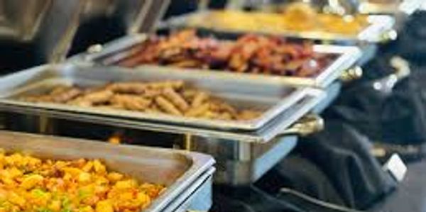 Buffet setup with various hot dishes in metal trays.