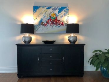 Modern black sideboard with lamps and colorful abstract painting.