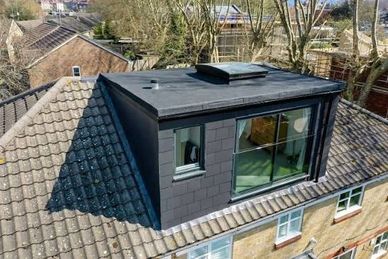 A modern rooftop extension with large windows on a traditional house.