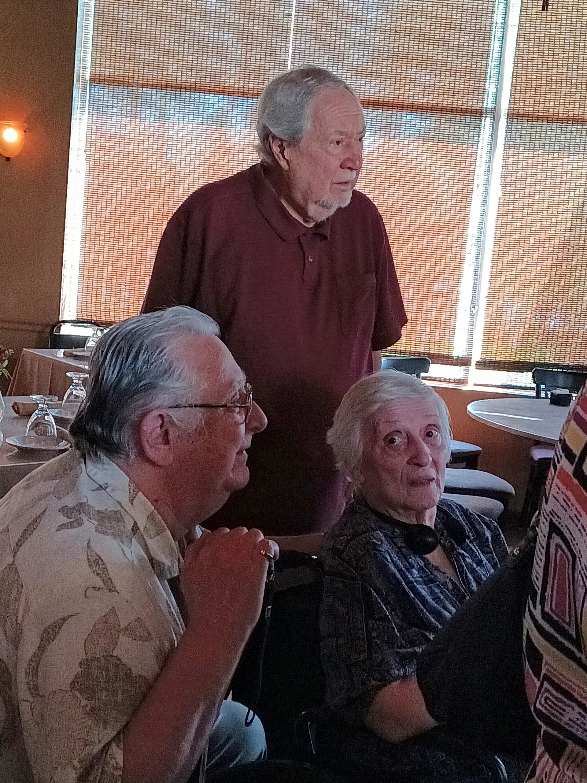 Three elderly people in a warmly lit restaurant setting.