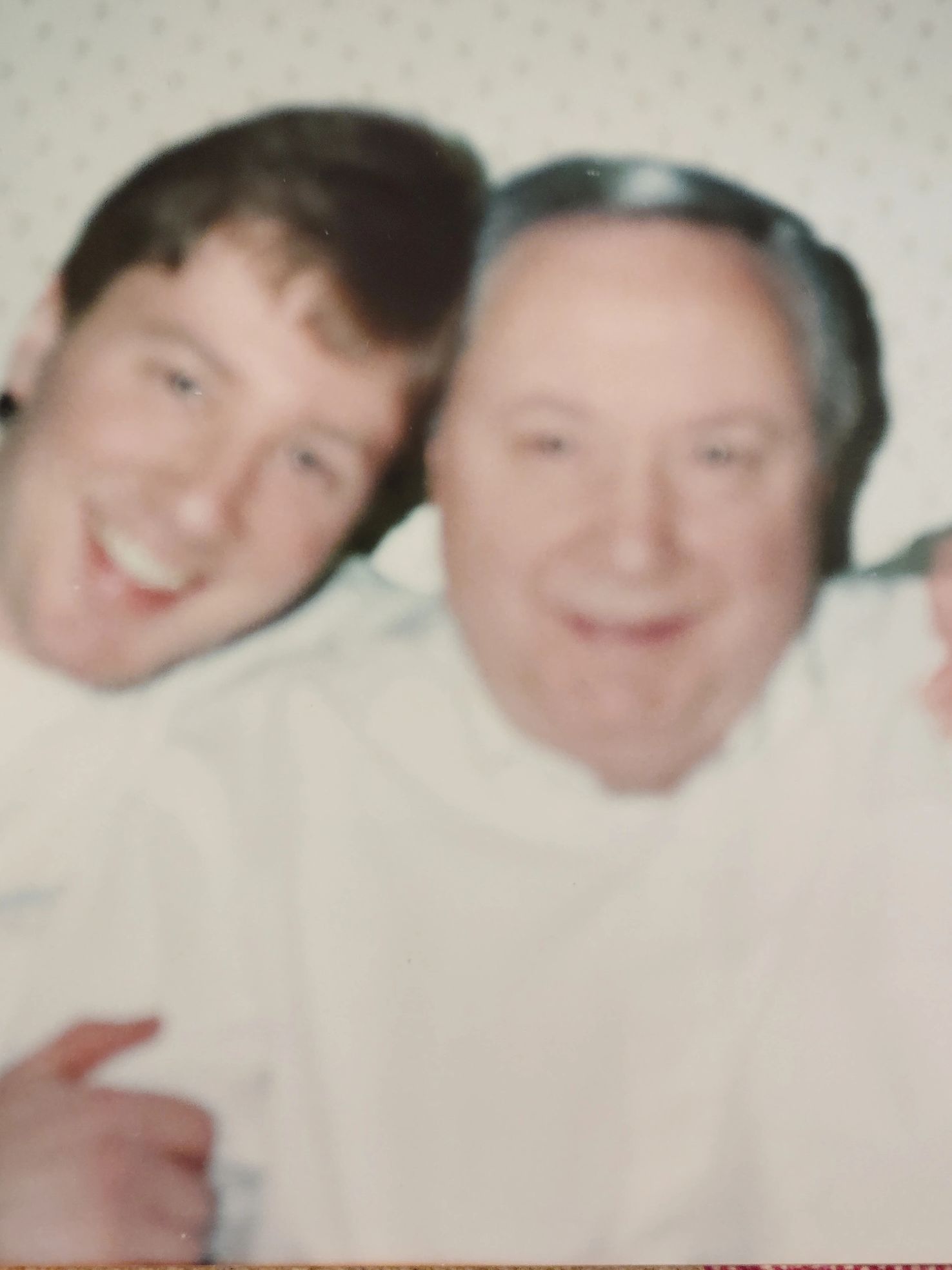 Blurred photo of two smiling men posing closely together.