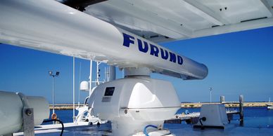 Marine radar on a ship deck with clear blue sky.