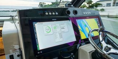 High-tech boat control panel with digital displays and steering wheel.