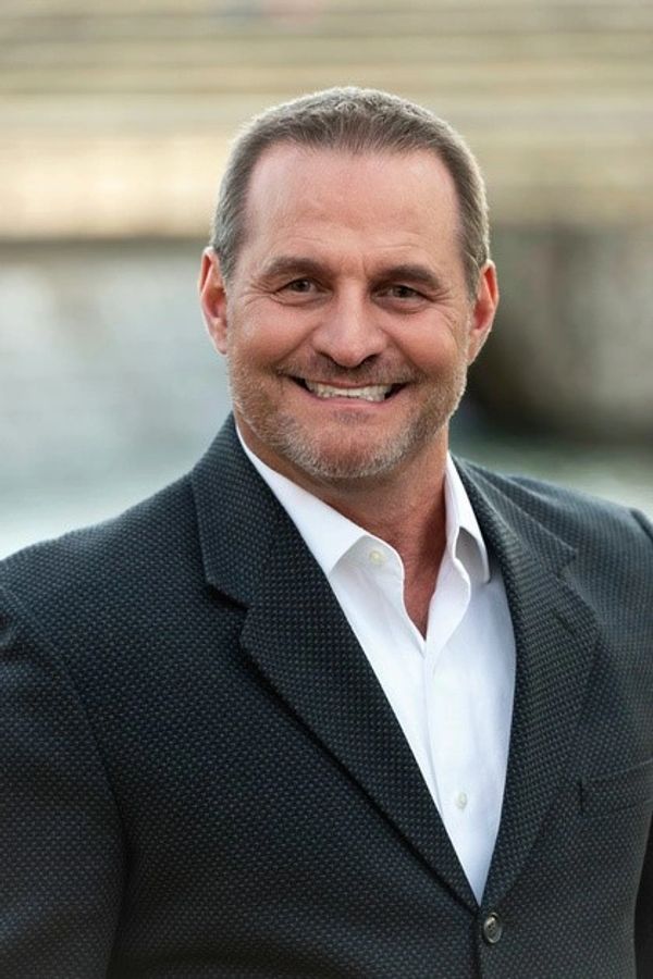 Smiling middle-aged man in suit jacket outdoors.