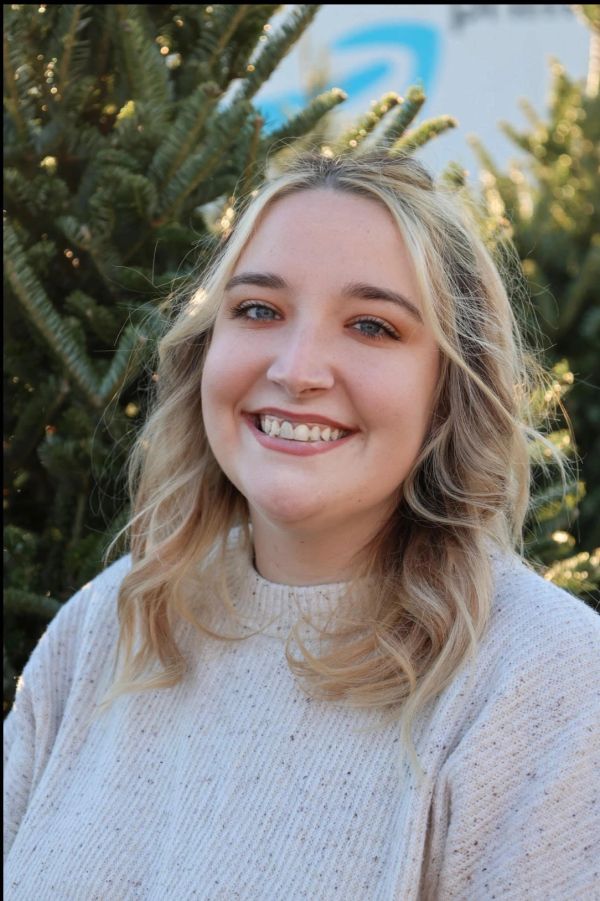 Smiling woman outdoors near trees.
