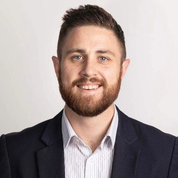 Portrait of a smiling man in a suit jacket and striped shirt.