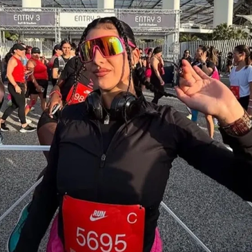 Runner posing at race event entrance with sunglasses and headphones.