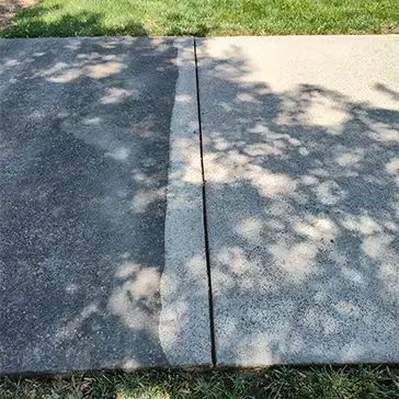 Concrete driveway pressure washed in Clarksville, TN, showing dirt removal and restored surface.