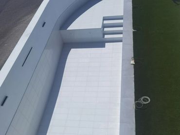 Piscina vacía con borde blanco y césped verde.
