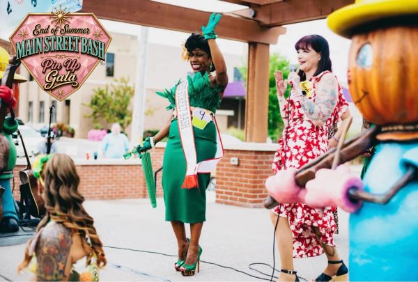 Woman in green dress waves at Main Street Bash Pin Up Gala.