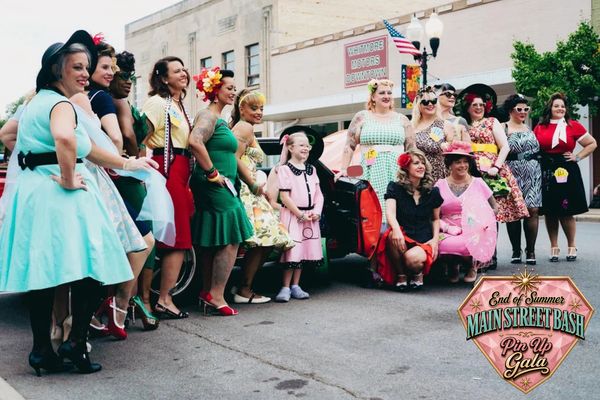 Group of women in vintage dresses at a pin-up gala.