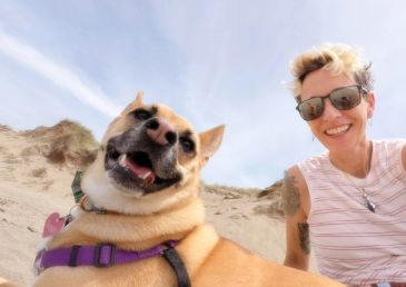 Smiling woman and dog enjoying time outdoors.