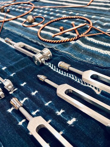 Tuning forks and copper wire arranged on a patterned fabric.