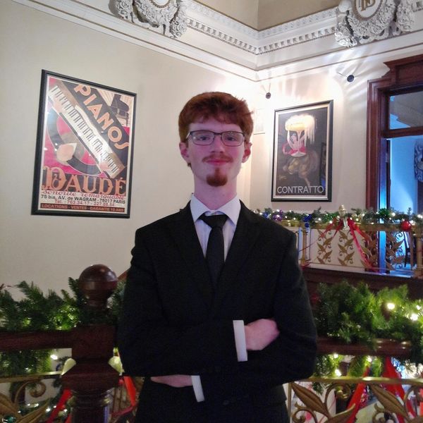Young man in a suit standing confidently in a decorated vintage interior.