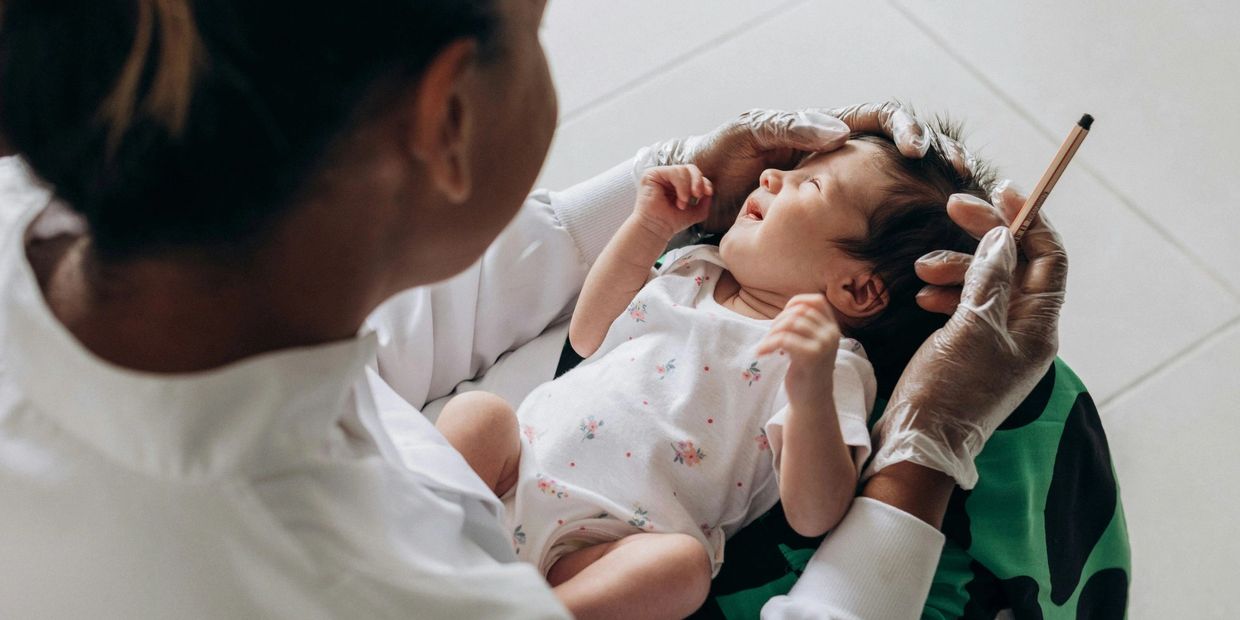 A healthcare worker holding and examining a newborn baby.
