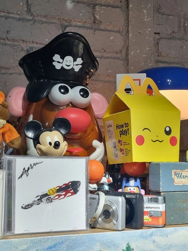 A playful collection of toys and cameras on a shelf against a brick wall.