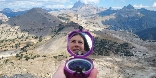 Image of a mountainous landscape and a geologic tool in a woman's hand.