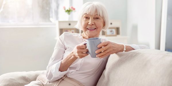 An elderly woman staying on the couch