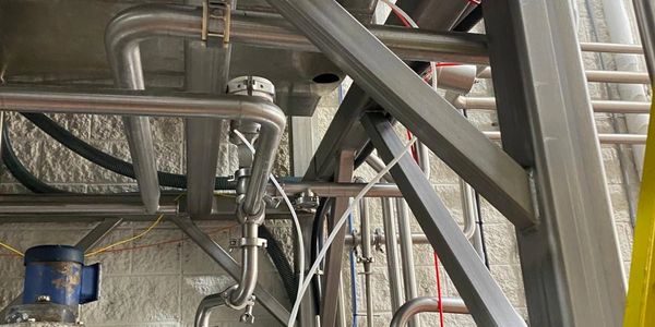 Industrial stainless steel tanks and pipes in a factory setting.