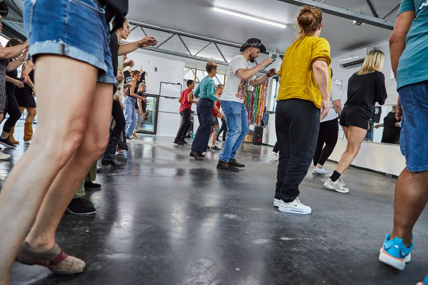 Group dance class with diverse participants practicing steps indoors.