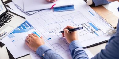 Person drawing architectural plans at a desk.