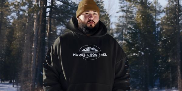 Man wearing a Moose & Squirrel Be Adventurous hoodie outside on a winter day.