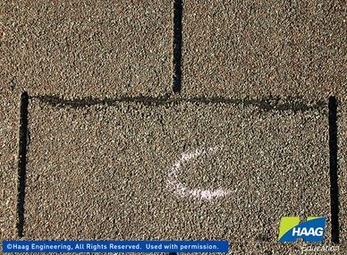 Asphalt composition shingle tab creased by wind.