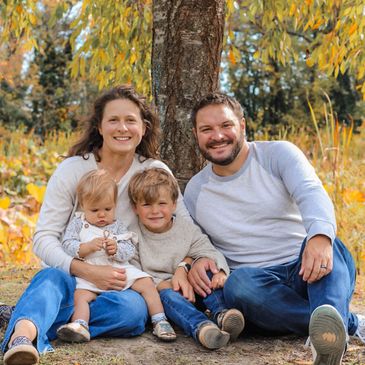 A happy family of four sitting outdoors in autumn.