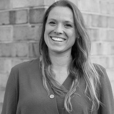Smiling woman with long hair in front of a brick wall.