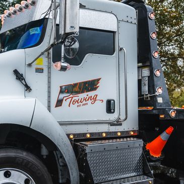 Close-up of a white towing truck with brand logo and orange traffic cone.