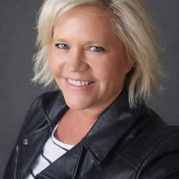 Smiling woman with blonde hair wearing a black leather jacket.