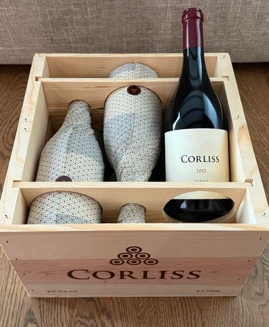 Wooden crate with a bottle of Corliss 2013 wine and ceramic containers.