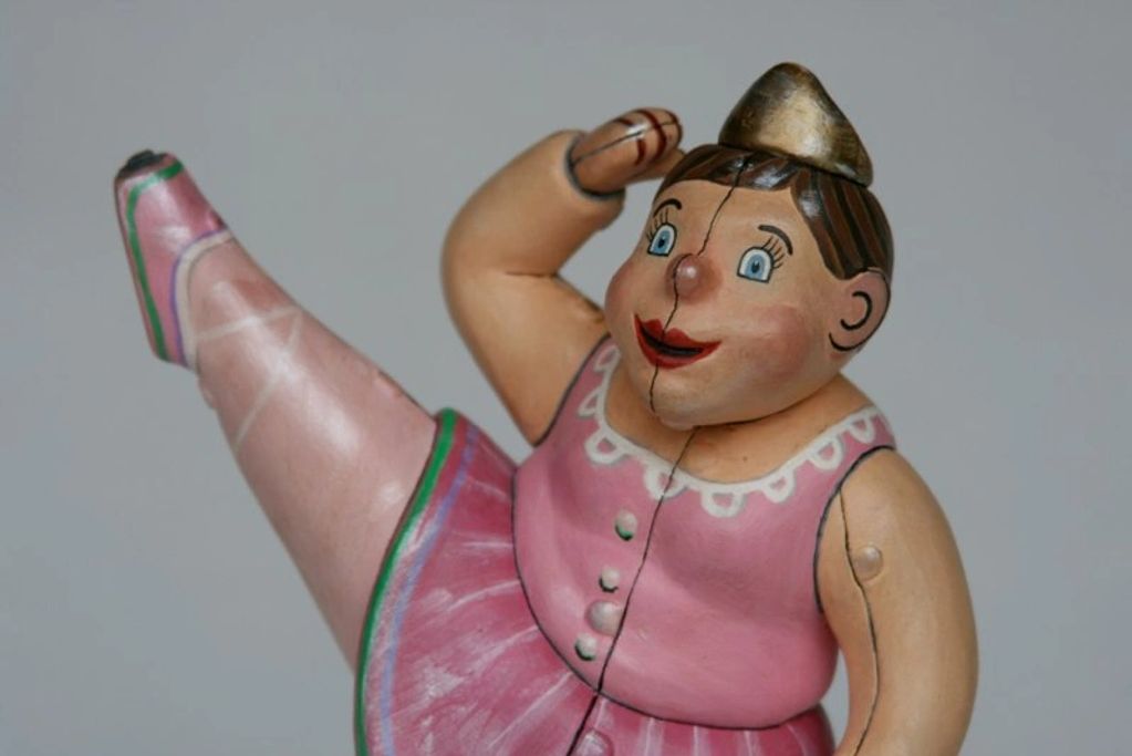 Vintage wooden ballerina doll in pink dress performing a kick.