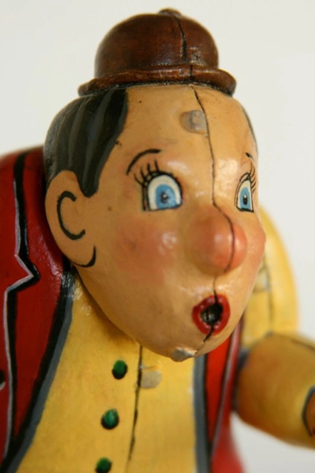 Close-up of a vintage painted toy clown with a cracked face.