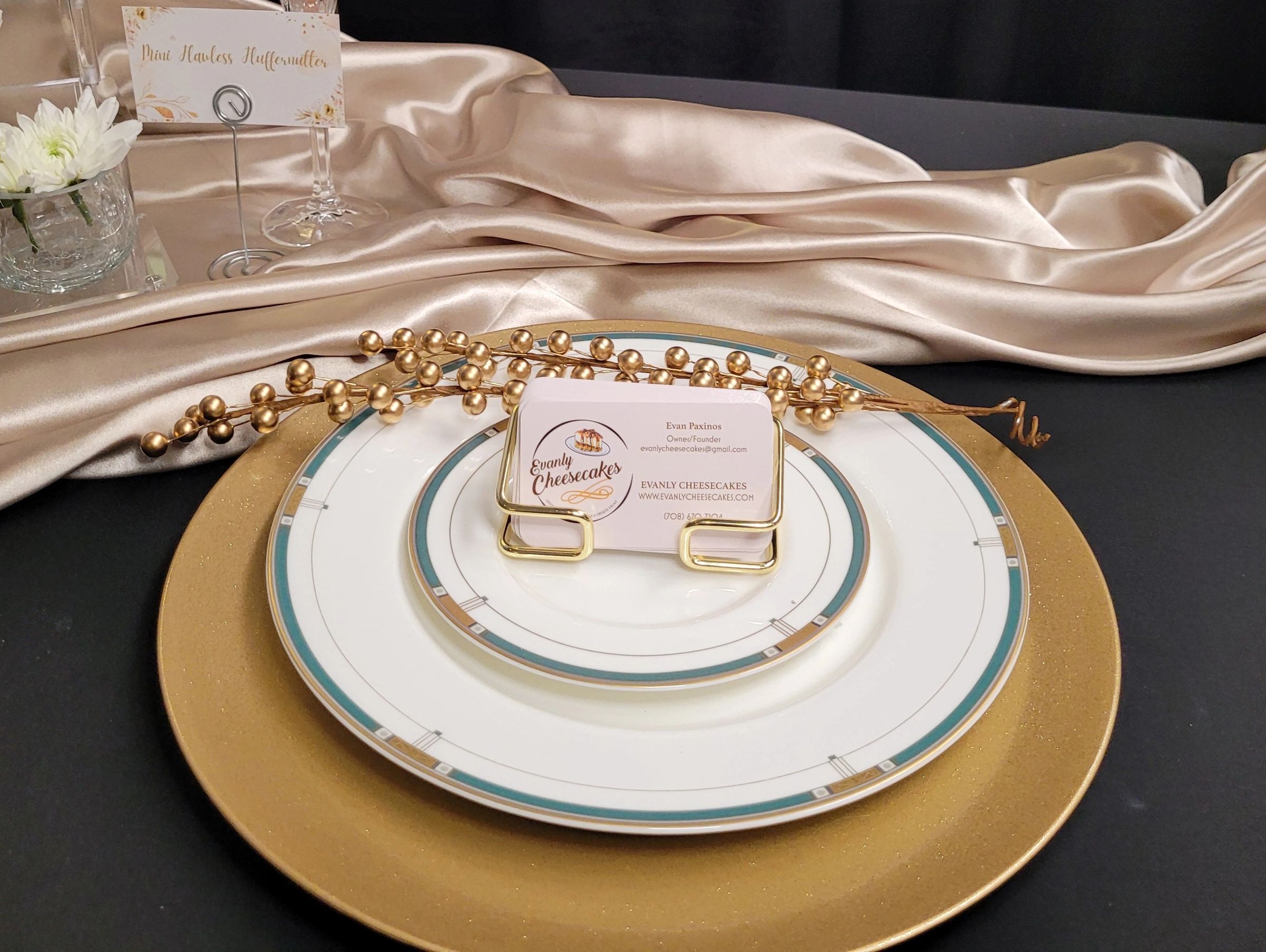 Elegant table setting with gold accents and a business card holder on fine china plates.