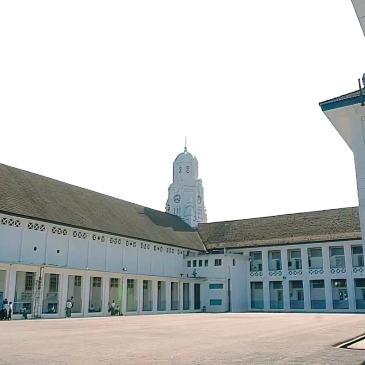Large courtyard with a clock tower and white buildings.
